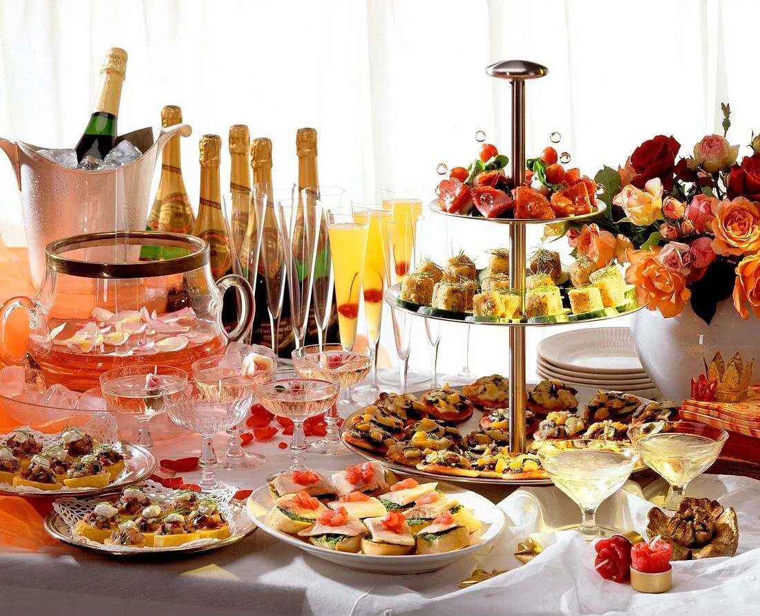 Buffet de cocktail : présentoir à étages de canapés, toasts, coupes de champagne, punch et bouquet de roses