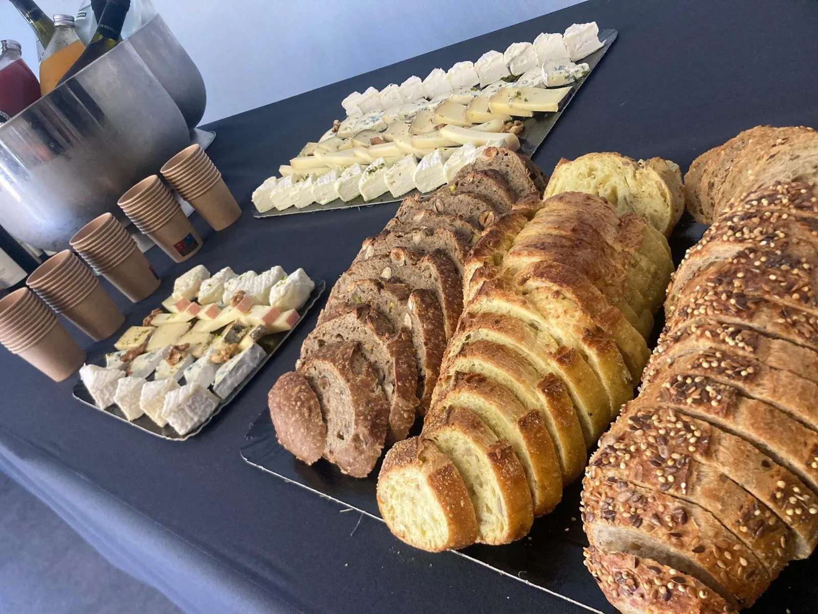 Buffet traiteur : pains tranchés, plateaux de fromages et boissons fraîches