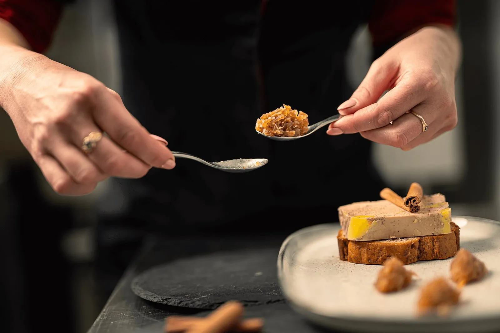 Les mains de la cheffe dressant une tranche de foie gras mi-cuit sur pain d'épices