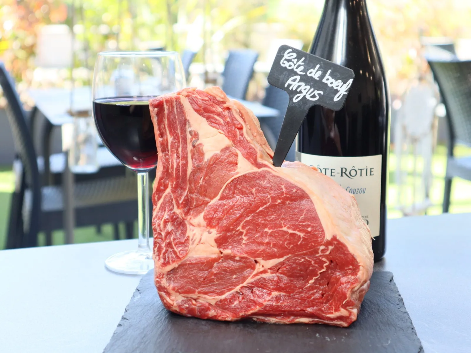 Côte de bœuf Angus sur ardoise avec un verre de Côte-Rôtie, sur la terrasse