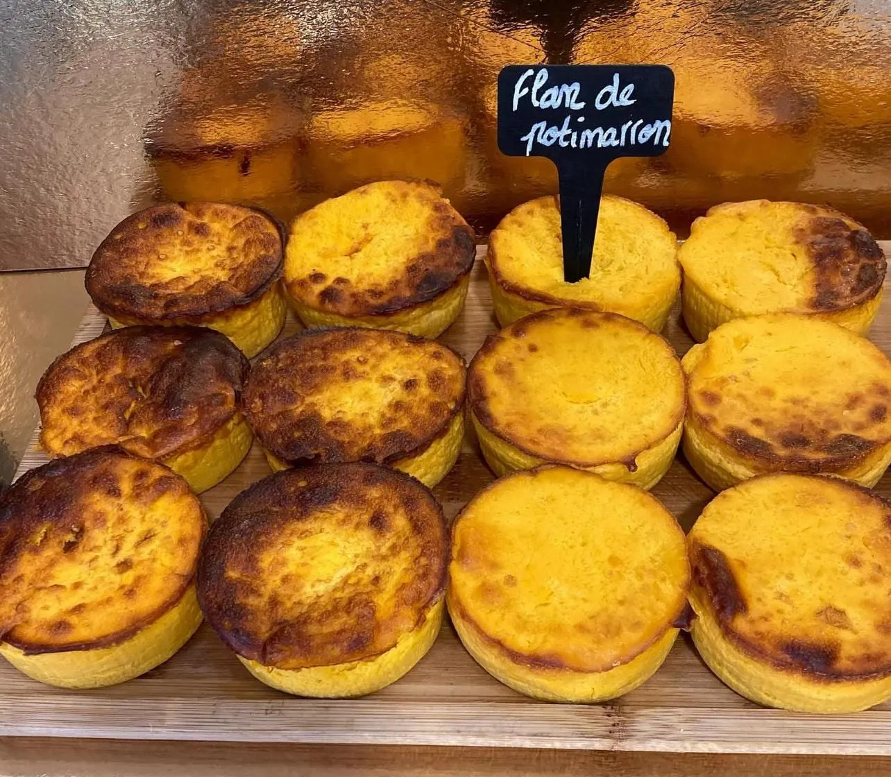 Flans de potimarron dorés alignés sur une planche en bois, avec leur ardoise
