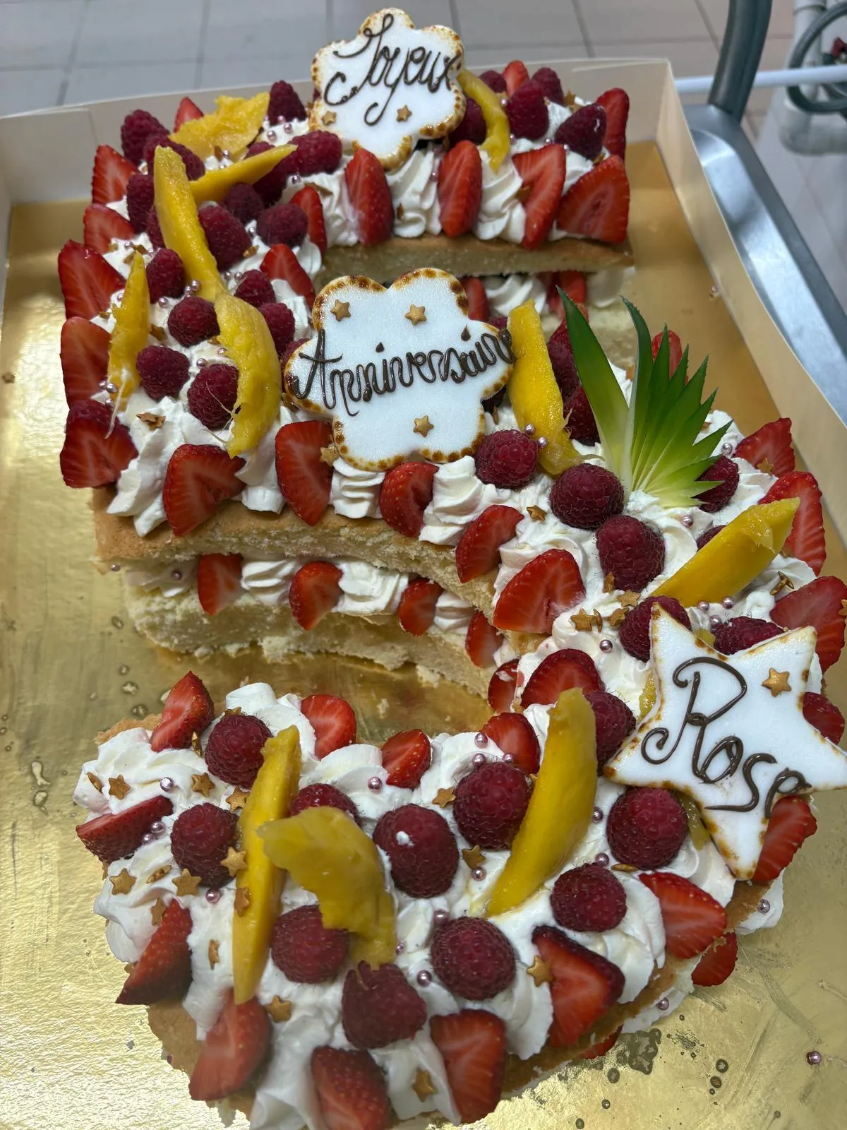 Gâteau d'anniversaire garni de chantilly, fraises, framboises et mangue