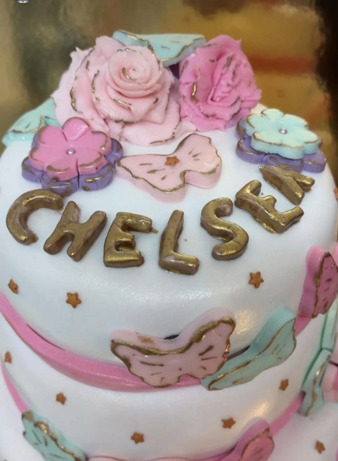 Gâteau à deux étages en pâte à sucre, roses et papillons pastel, prénom doré