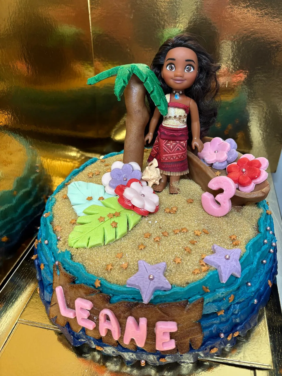 Gâteau d'anniversaire sur le thème de Vaiana : plage, palmier et fleurs en sucre