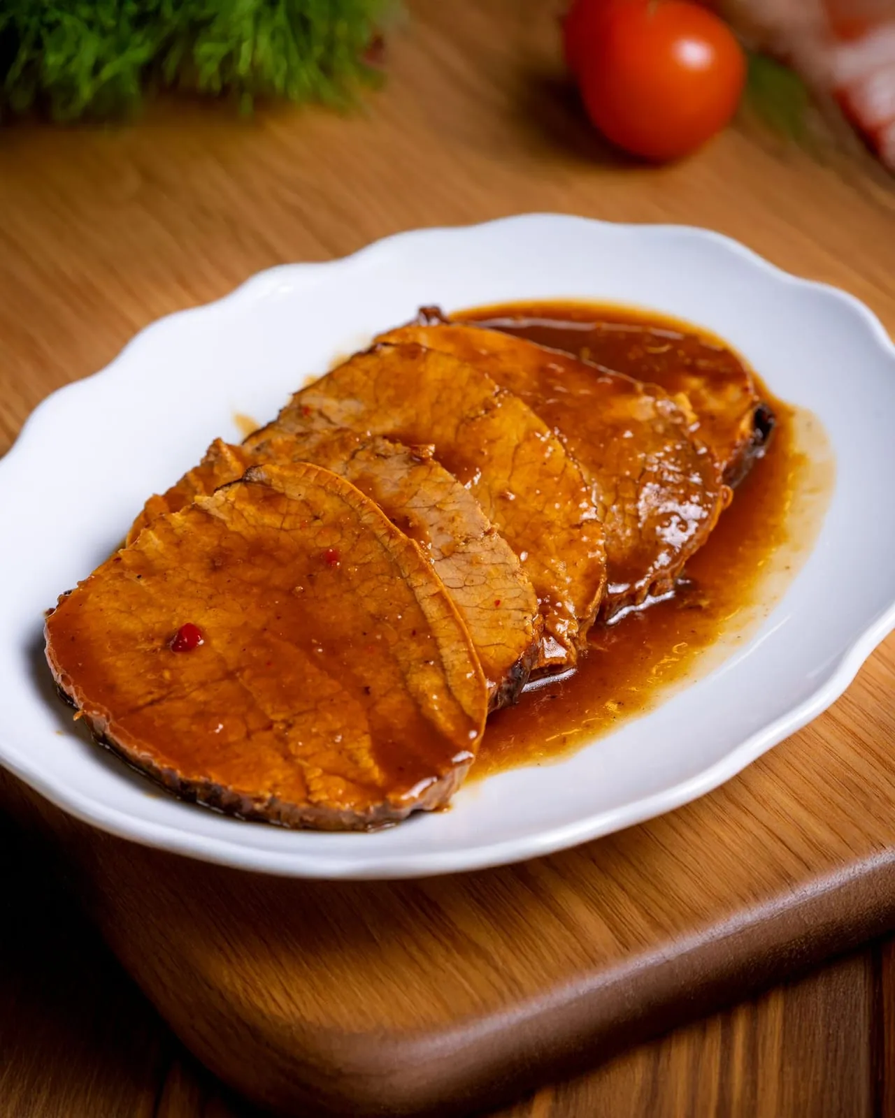 Tranches de rôti nappées d'une sauce brune, servies sur une assiette blanche