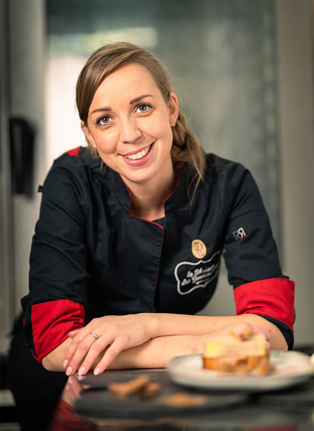 Nathanaëlle Martin, cheffe et fondatrice, en veste de cuisine, devant une assiette de foie gras