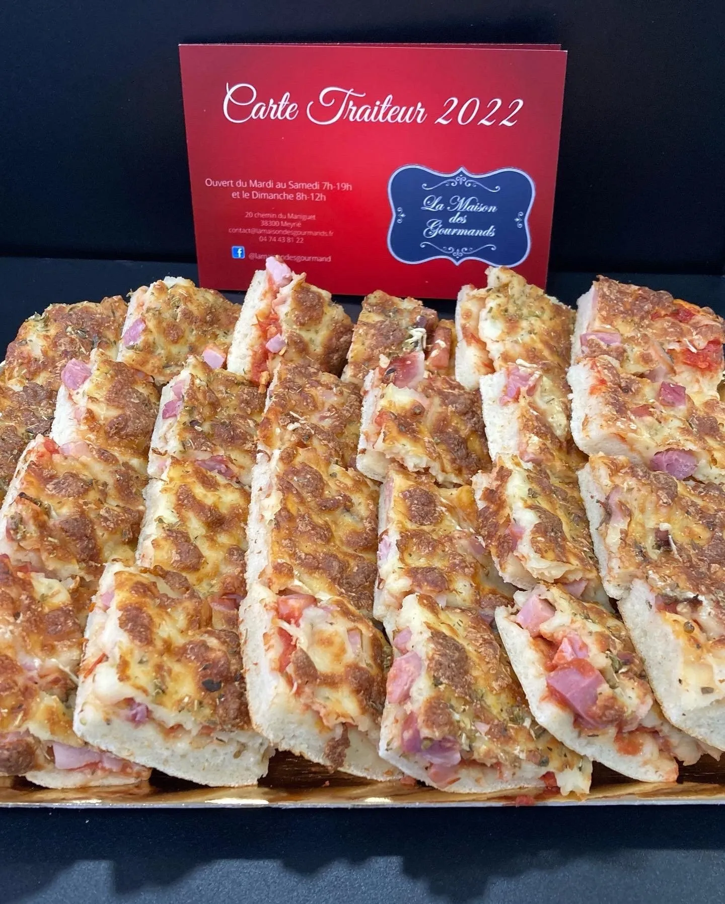 Plateau de pizzas coupées en parts, au jambon et à la tomate, dorées au four