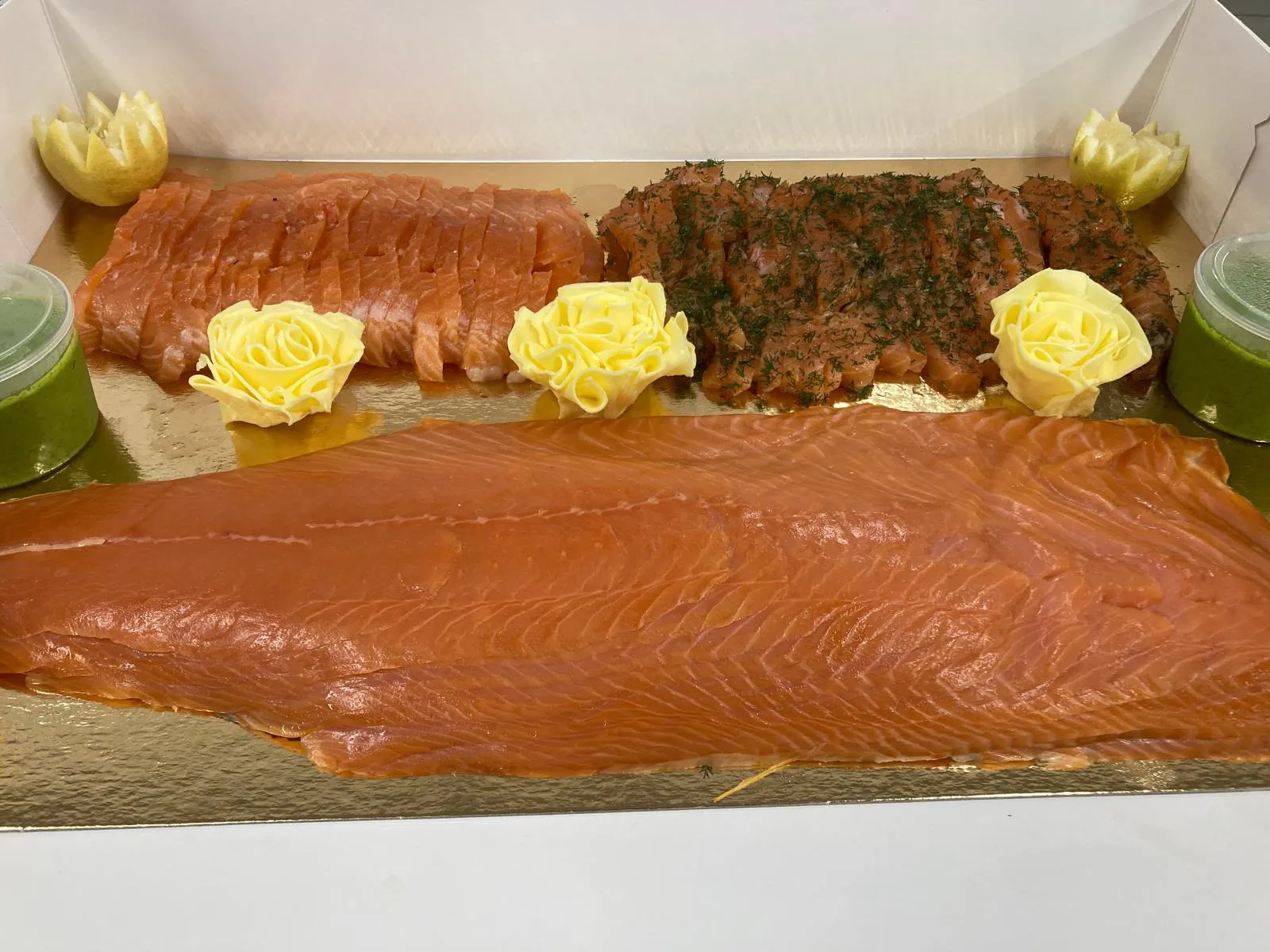 Plateau de saumons : saumon fumé tranché, gravlax à l'aneth et filet entier, roses de beurre, citrons sculptés et sauce verte