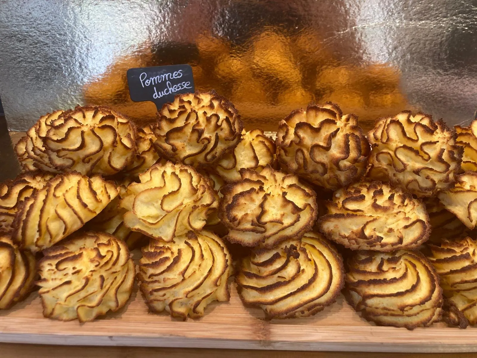 Pommes duchesse dorées au four, empilées sur une planche en bois