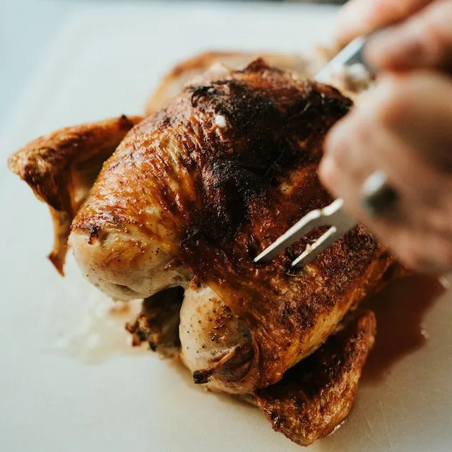 Découpe d'un poulet fermier rôti à la peau dorée