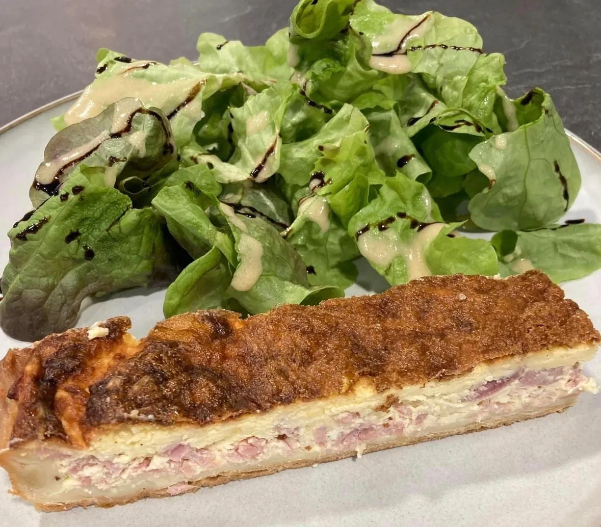 Part de quiche lorraine dorée, servie avec une salade verte
