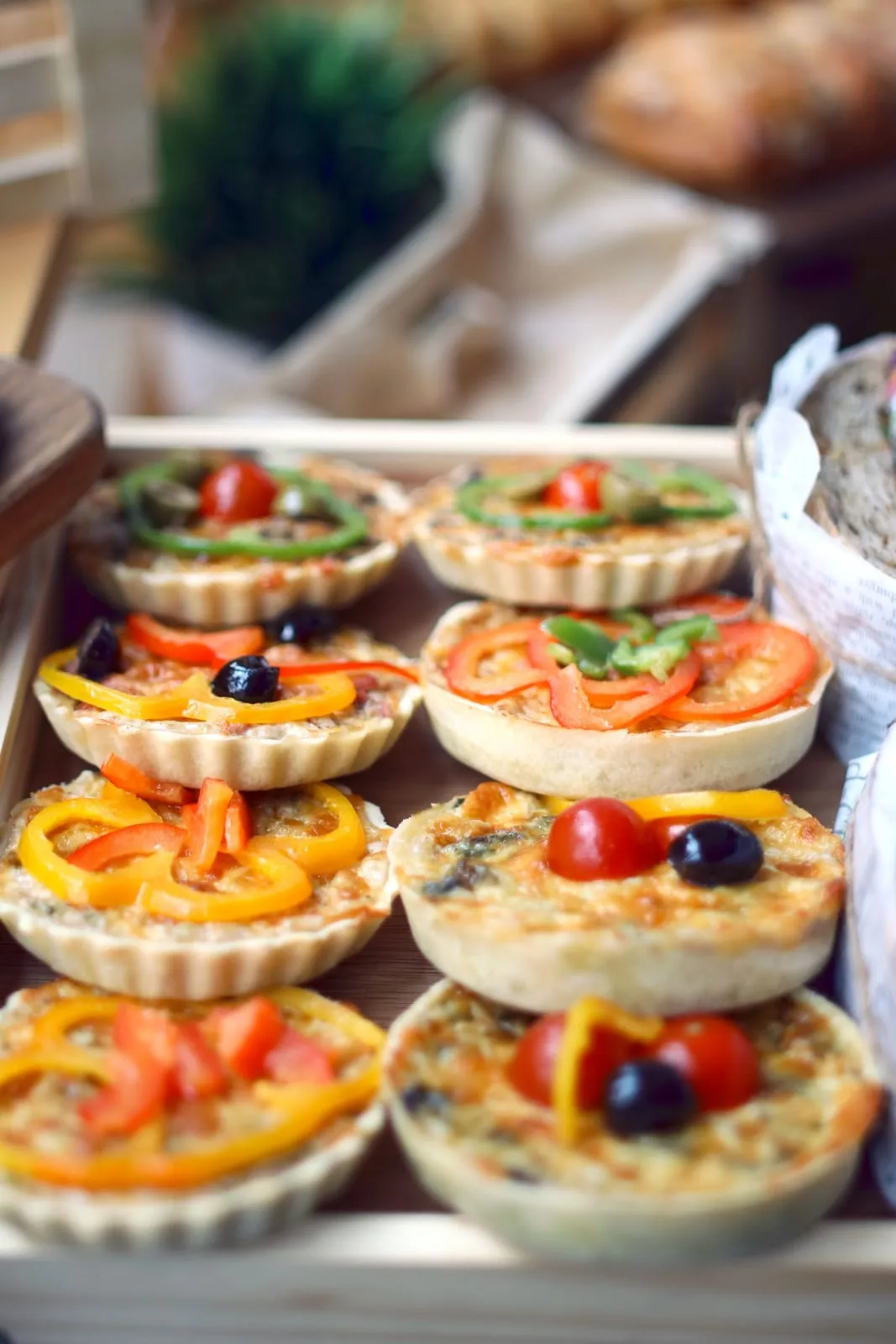 Petites tartelettes salées garnies de poivrons, de tomates et d'olives, sur un plateau