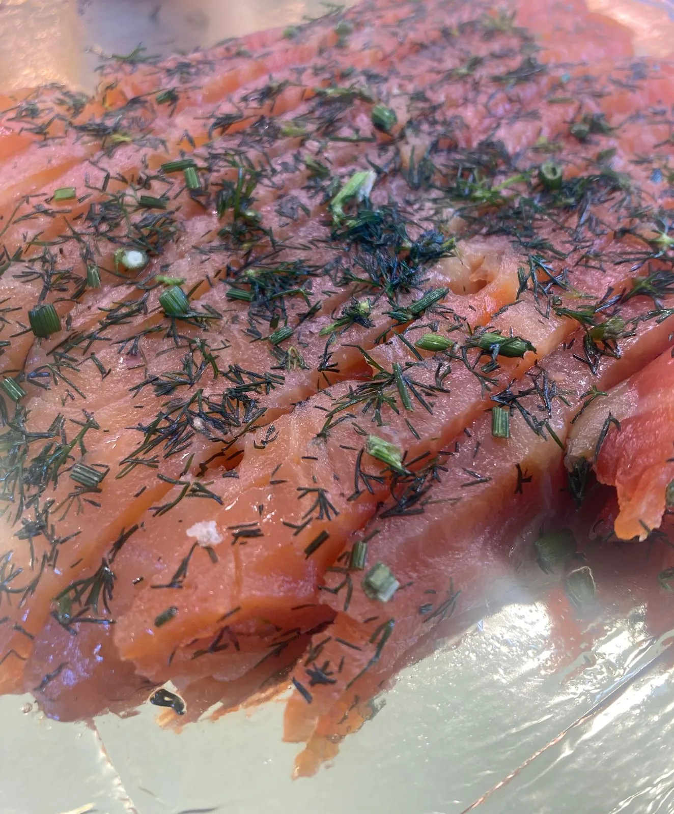 Saumon gravlax tranché, parsemé d'aneth frais et de ciboulette