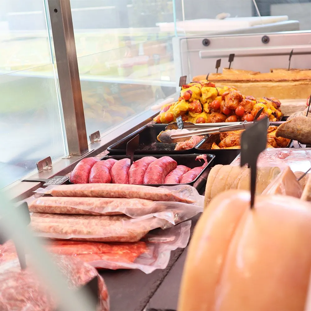 Gros plan sur la vitrine : saucisses maison, plats cuisinés et pâté en croûte